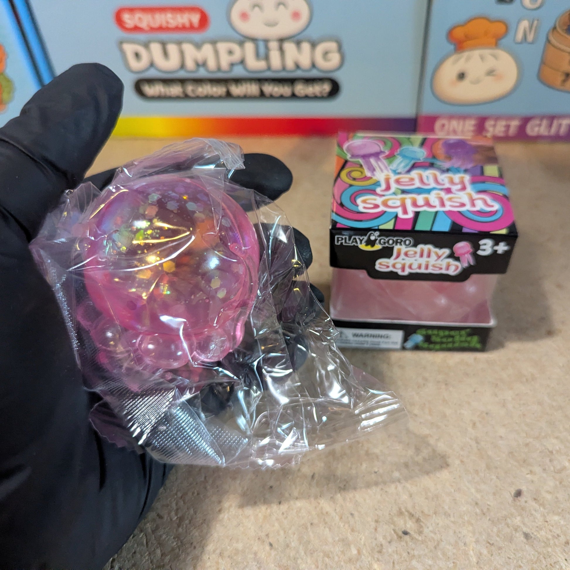 Pink jellyfish squish toy with tentacles, slow-rising plush from Ralphie's Funhouse, soft and squeezable for stress relief.