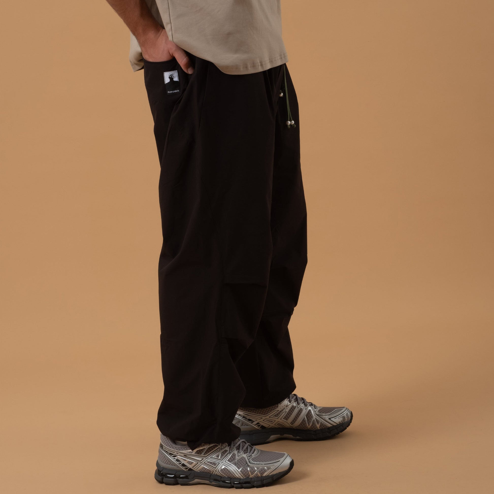 Black pleated field pants by Shuren Projects made of Teflon™ polyester, featuring a tailored, durable bottom style.