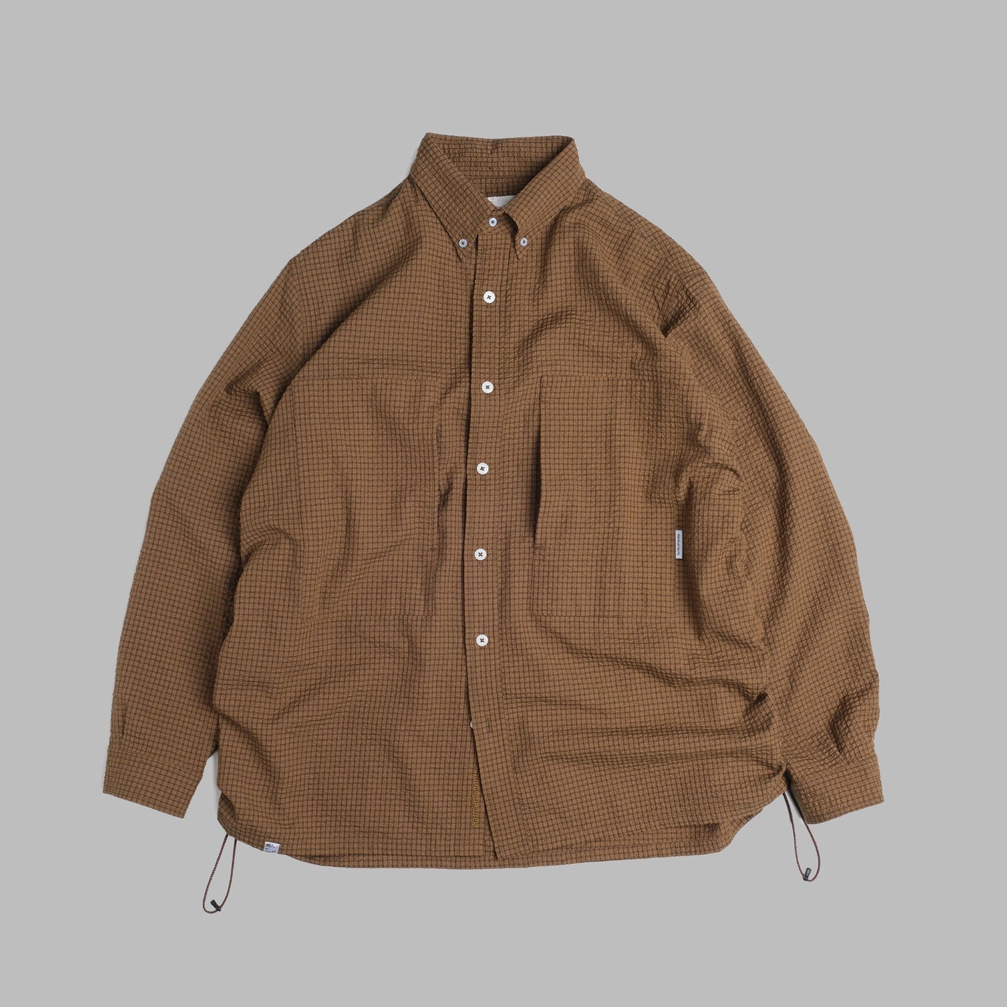 Brown checkered sidepull shirt made of seersucker cotton by Shuren Projects, shown in a close-up of the fabric and design.