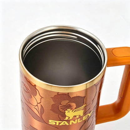 Orange STANLEY Quencher H2.0 FlowState tumbler featuring Karol G branding, double-wall insulation, and a spill-resistant lid.