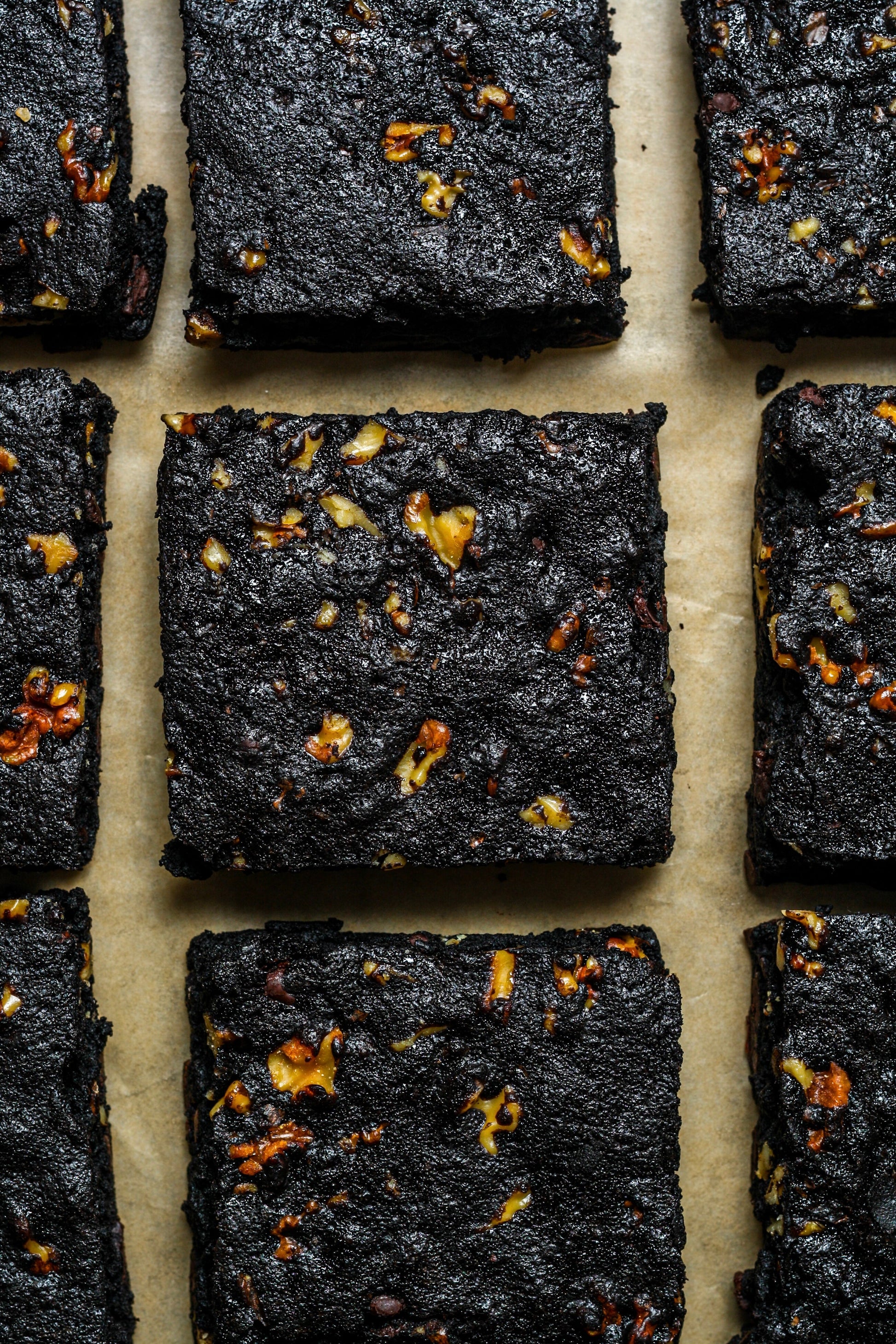 Four walnut protein brownies from Sweet Addison's, showcasing rich chocolate and walnut toppings on a white plate.