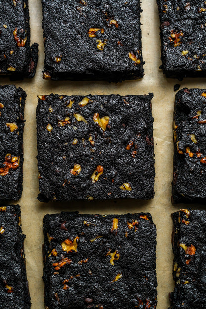 Four walnut protein brownies from Sweet Addison's, showcasing rich chocolate and walnut toppings on a white plate.