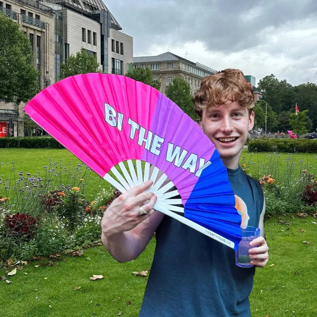 Hand fan by The Gay Fan Club featuring "Bi the Way" design, colorful fabric with a wooden handle.