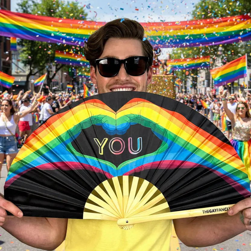 Hand fan by The Gay Fan Club with "Love You" design, featuring colorful fan blades and a wooden handle.