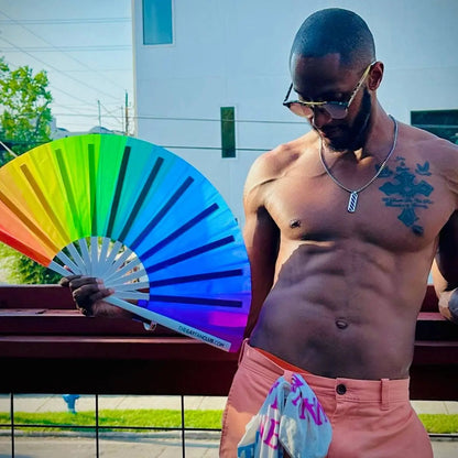 Colorful Over The Rainbow hand fan by The Gay Fan Club featuring vibrant rainbow stripes and lightweight wooden handles.