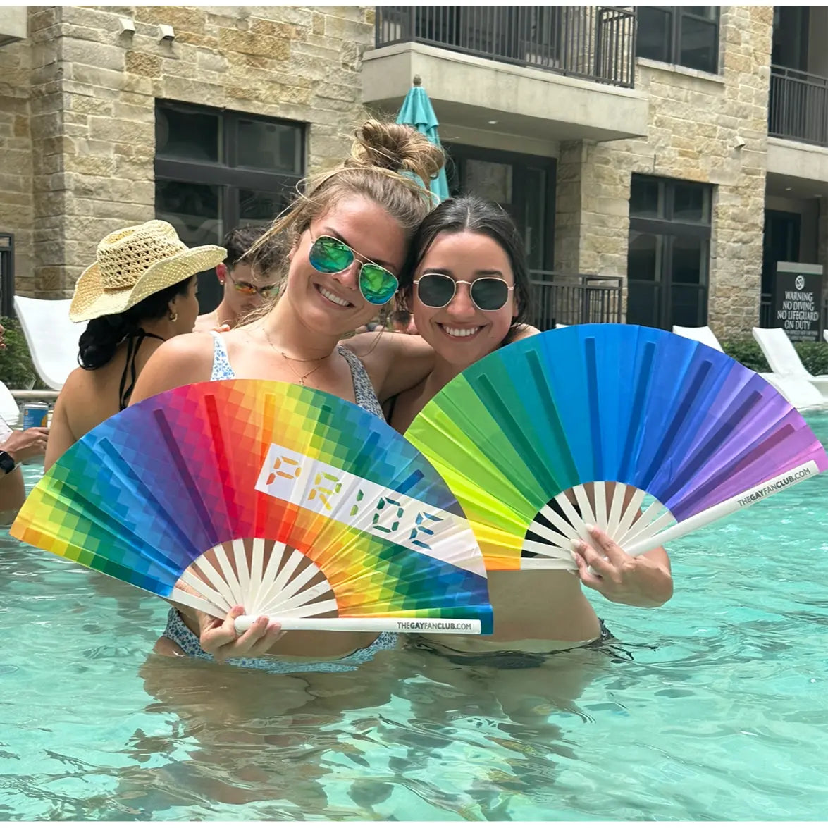 Colorful hand fan from The Gay Fan Club featuring a rainbow design, perfect for summer or LGBTQ+ pride events.