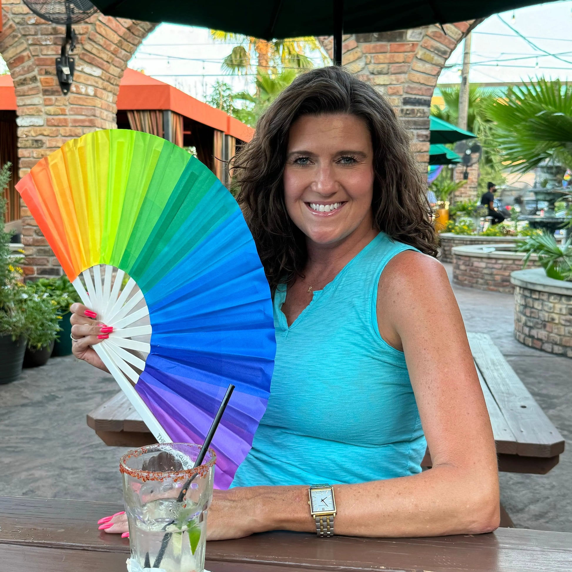 Colorful over the rainbow hand fan by The Gay Fan Club with vibrant rainbow design and wooden handle.