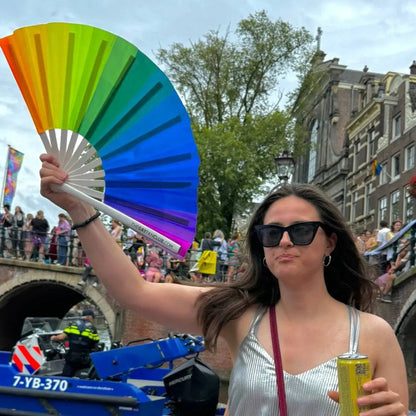 Colorful Over The Rainbow hand fan by The Gay Fan Club with vibrant rainbow stripes and a compact, foldable design.