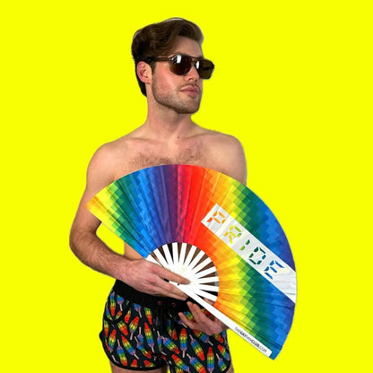 Hand fan by The Gay Fan Club featuring vibrant rainbow Pride colors and a fan-shaped design.
