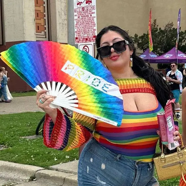 Hand fan by The Gay Fan Club featuring vibrant rainbow Pride colors, perfect for supporting LGBTQ+ pride events.