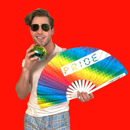 Hand fan with rainbow Pride design by The Gay Fan Club, featuring colorful rainbow stripes and a compact, portable style.