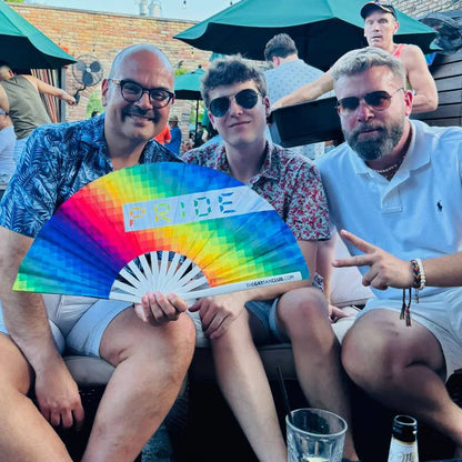 Hand fan with rainbow Pride design by The Gay Fan Club, featuring vibrant rainbow colors and a foldable hand-held style.