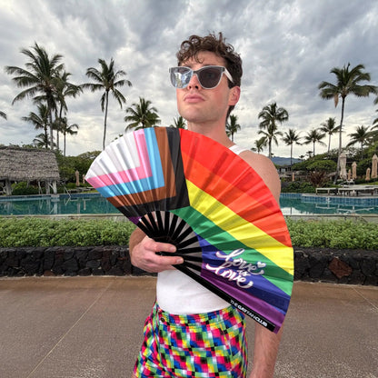 Hand fan featuring the Pride rainbow flag design from The Gay Fan Club, showcasing vibrant rainbow colors and a fan shape.