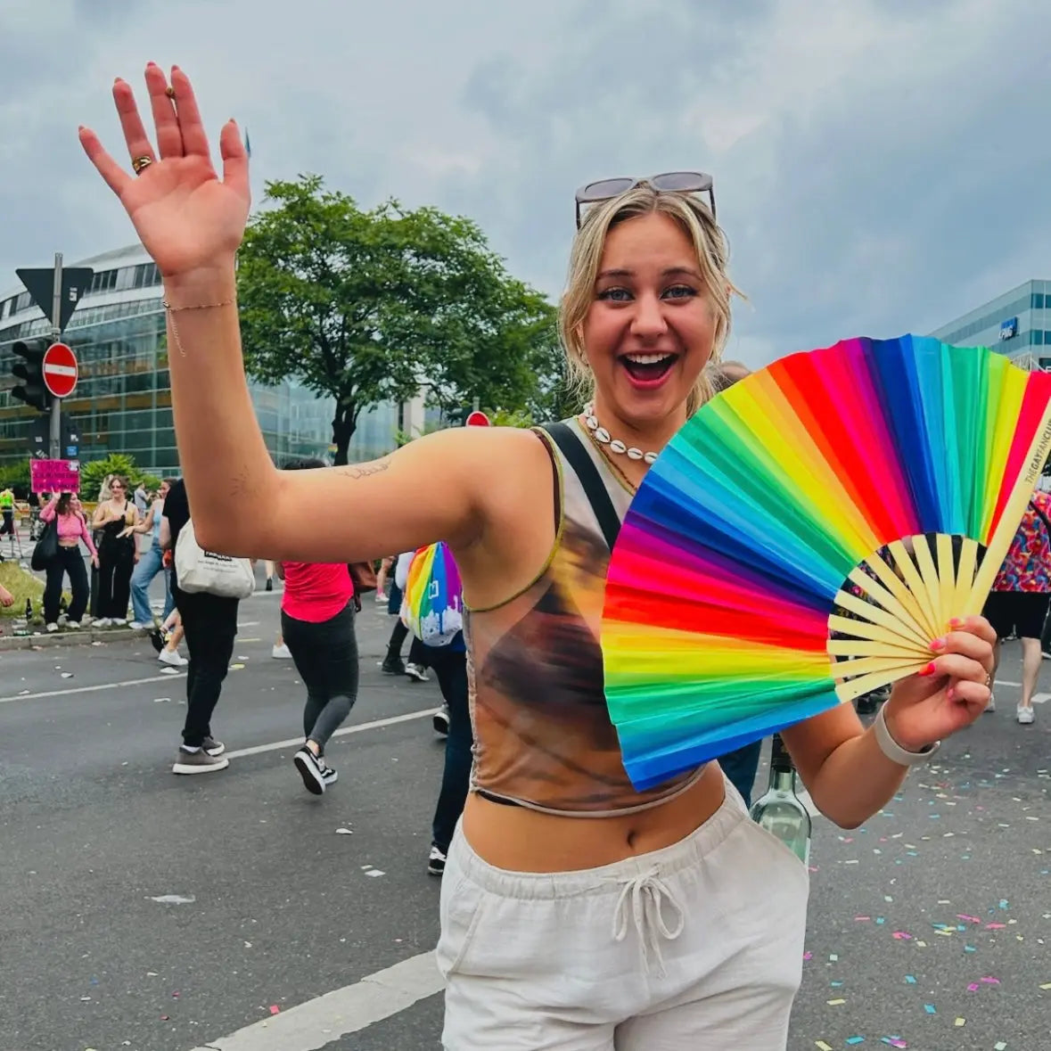 Rainbow folding hand fan by The Gay Fan Club, featuring vibrant rainbow colors and a compact, foldable design.