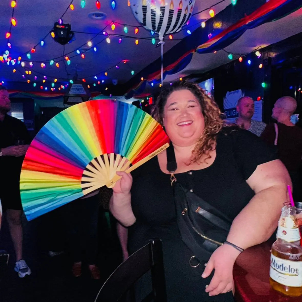 Rainbow folding hand fan by The Gay Fan Club, featuring vibrant rainbow colors and a compact, foldable design.