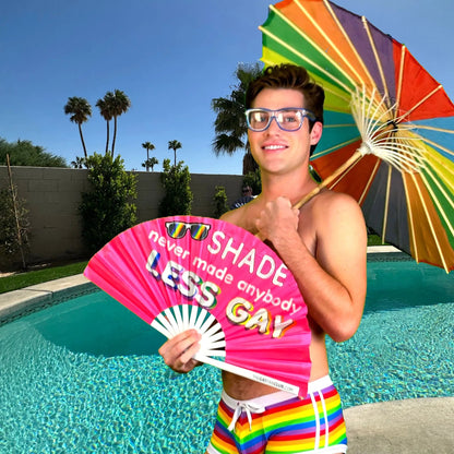 Hand fan from The Gay Fan Club featuring the "Shade Never Made Anybody Less Gay" design, with colorful printed text on fabric.