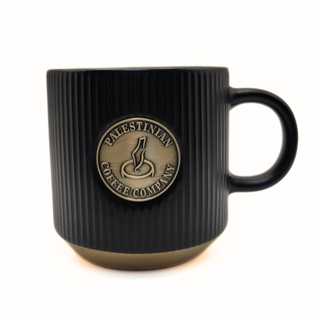 Black ceramic mug from The Palestinian Coffee Company with Pali Coffee Co branding, ideal for coffee or tea.