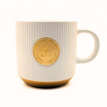 Black ceramic mug from The Palestinian Coffee Company featuring Pali Coffee Co branding and Palestinian-inspired design.