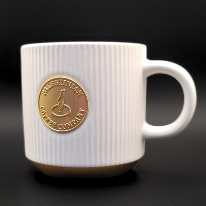 Black ceramic mug from The Palestinian Coffee Company with Pali Coffee Co branding, ideal for coffee or tea.