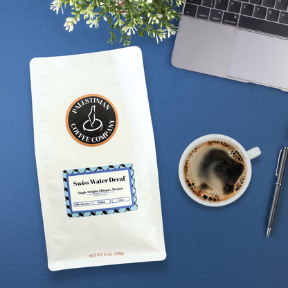 Whole bean Swiss Water decaf coffee by The Palestinian Coffee Company, showcasing dark roasted beans in a natural setting.